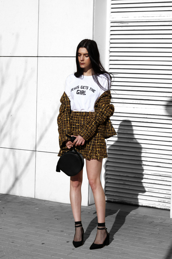 Bộ skirt suit họa tiết tưởng chừng già nua trở nên bắt mắt không ngờ khi được cô nàng này phối cùng T-shirt in chữ và giày cao gót phối tất lưới cá tính mà sexy.
