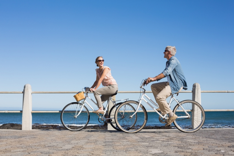 Happy casual couple going for a bike ride on the pier