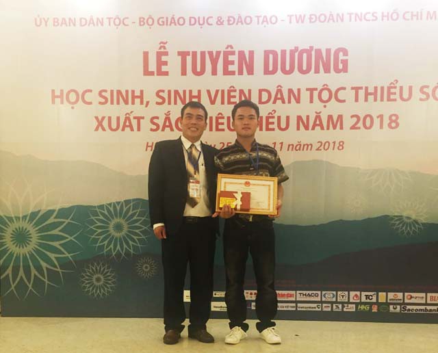 Lô Văn Anh và thầy trưởng khoa Công nghệ ô tô, Trường Cao đẳng Nghề Việt - Đức chụp ảnh lưu niệm tại lễ tuyên dương học sinh, sinh viên dân tộc thiểu số xuất sắc tiêu biểu năm 2018. 