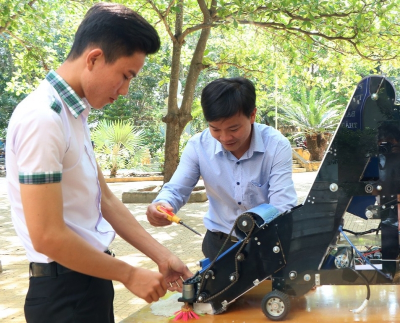 Thạc sĩ Nguyễn Trần Thái Vũ đang hỗ trợ Thực và Nguyên kiểm tra lại máy trước khi cho khởi động.