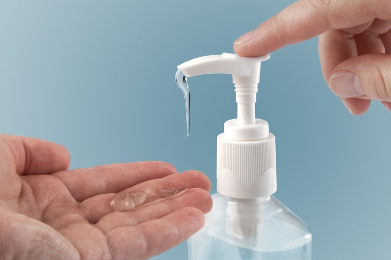 Photograph of a finger pumping sanitizer onto hand