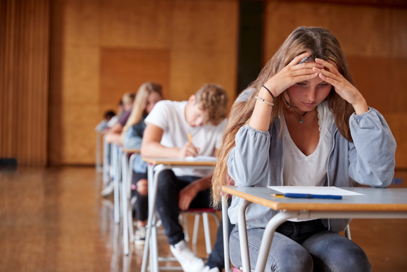Anxious teenage student sitting examination in school hall