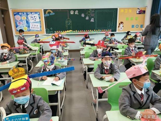 Học sinh một trường tiểu học tại thành phố Hàng Châu, tỉnh Chiết Giang, đội mũ tự chế để đảm bảo giãn cách với các bạn trong lớp vào ngày đầu đi học lại.