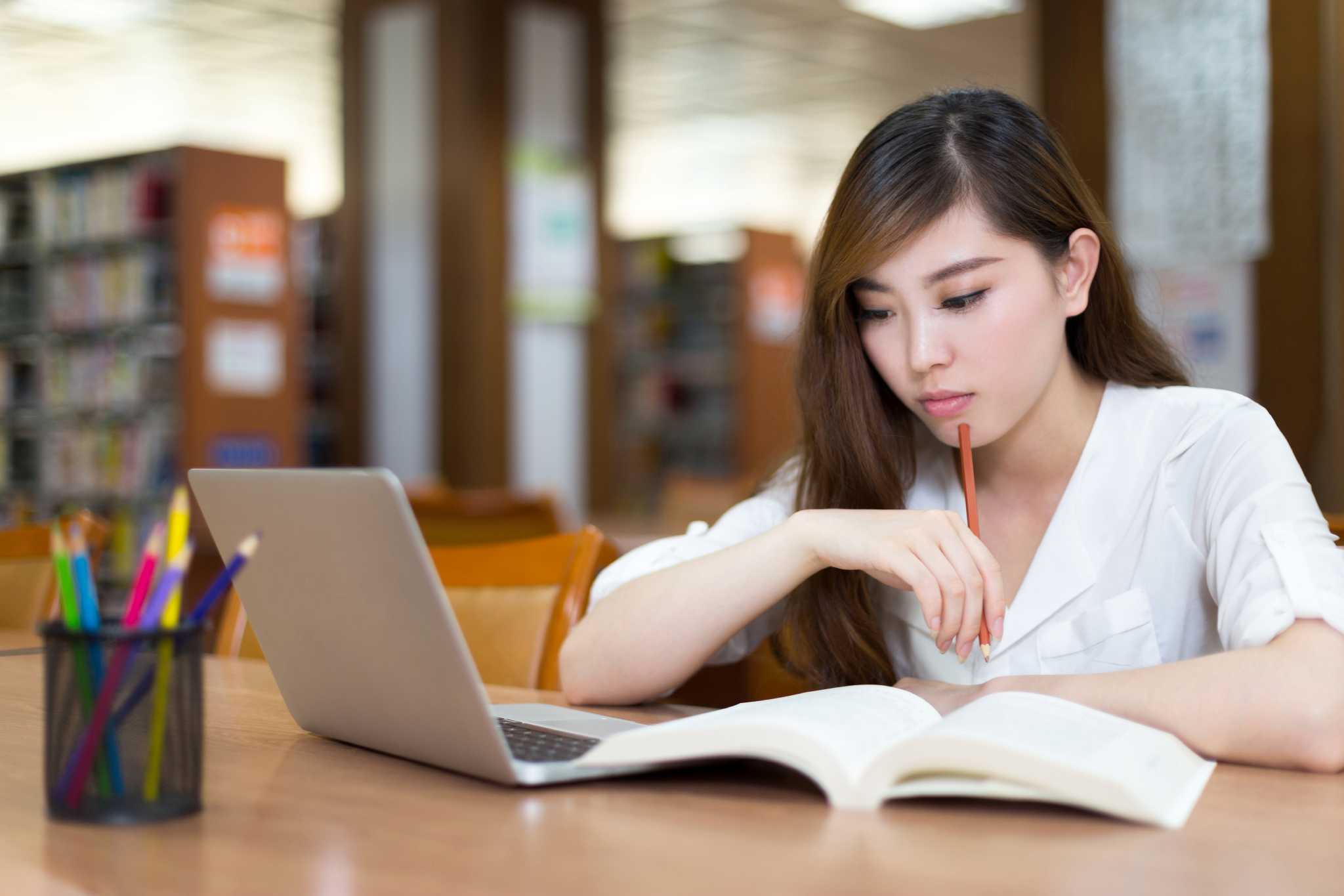 Beautiful asian female student using laptop for study in library