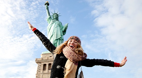 A beautiful young blonde woman at The Statue of Liberty in New York.