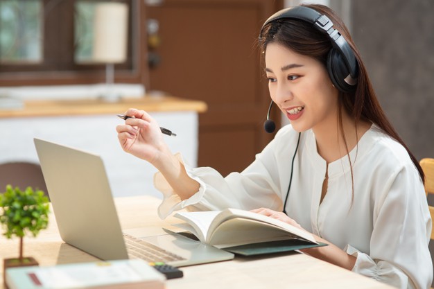 smiling-asian-young-female-using-headset-looking-laptop-screen-listen-learning-online-courses_56587-700
